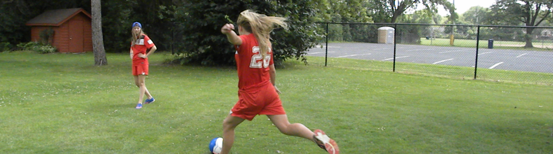 Girls playing soccer in red jersey uniforms