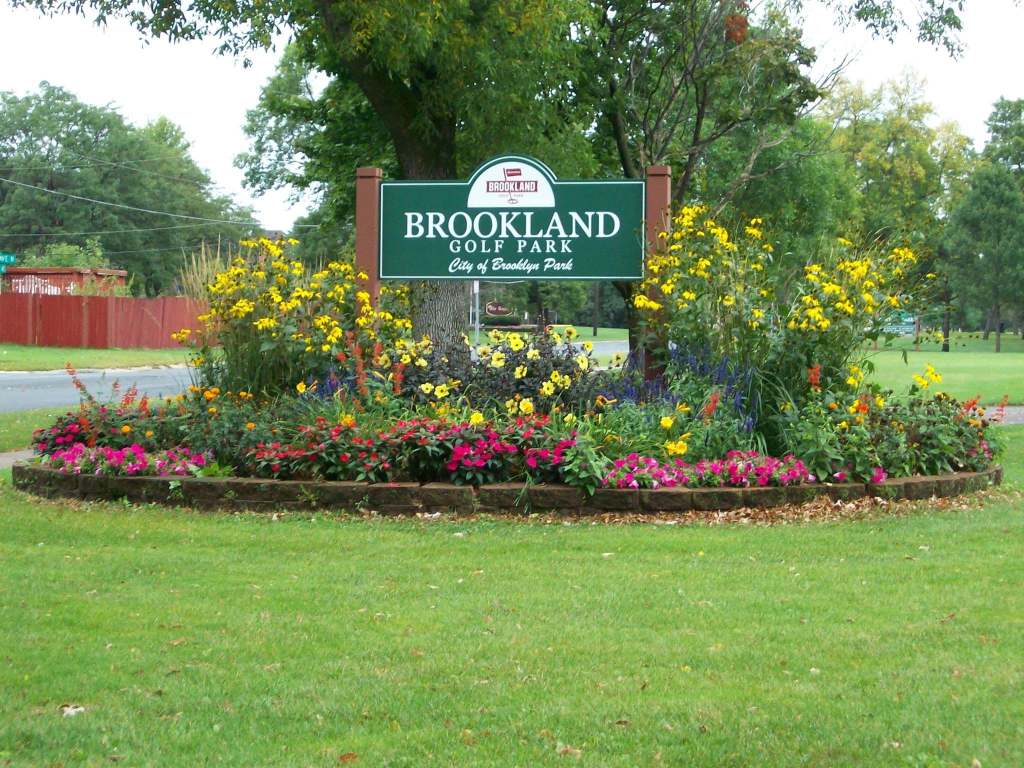 The Brookland Golf Park sign surrounded by pink and yellow flowers.